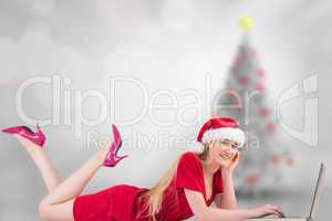 Composite image of festive blonde using a laptop