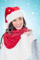 Composite image of festive brunette in winter wear holding shopp