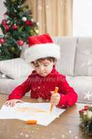 Composite image of festive little boy writing wish list