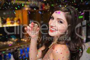 Composite image of pretty brunette drinking a shot