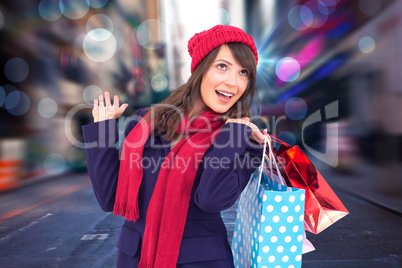 Composite image of happy brunette in winter clothes holding shop