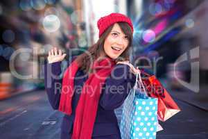 Composite image of happy brunette in winter clothes holding shop