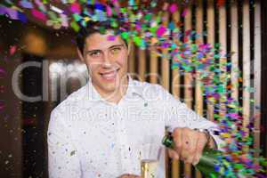 Composite image of handsome man smiling at camera pouring champa