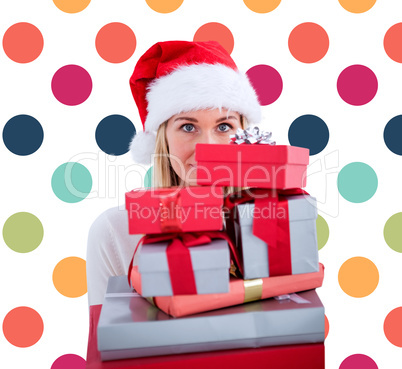 Composite image of festive blonde holding pile of gifts