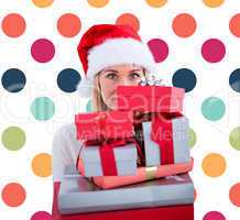 Composite image of festive blonde holding pile of gifts