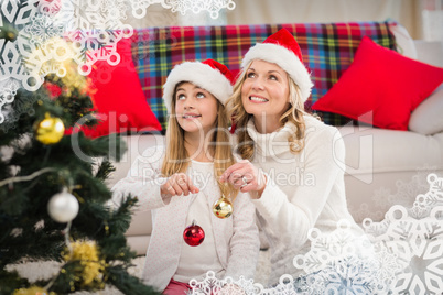 Composite image of festive mother and daughter decorating christ