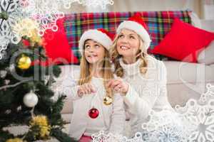 Composite image of festive mother and daughter decorating christ