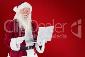 Composite image of santa pays with credit card on a laptop