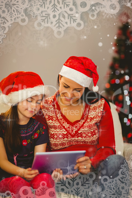 Composite image of festive mother and daughter using tablet