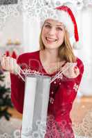 Composite image of festive blonde opening gift bag while looking at the camera