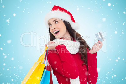 Composite image of festive brunette holding shopping bags and cr