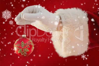 Composite image of santas hand is holding a christmas bulb