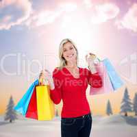 Composite image of happy blonde holding shopping bags