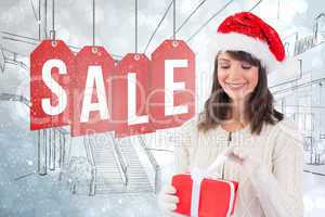 Composite image of festive brunette in santa hat opening a gift