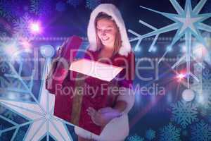 Composite image of festive pretty brunette opening a gift