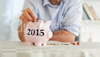 Composite image of change being put into piggy bank