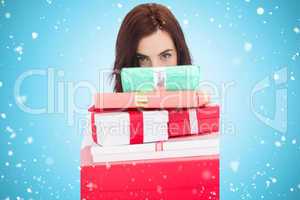 Composite image of portrait of a brunette holding pile of gifts