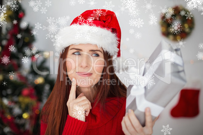 Composite image of festive redhead holding christmas gift