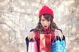 Composite image of shocked brunette opening gift bag