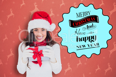 Composite image of festive brunette in santa hat holding gift