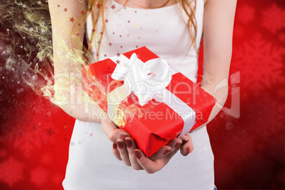 Composite image of woman holding red and white gift