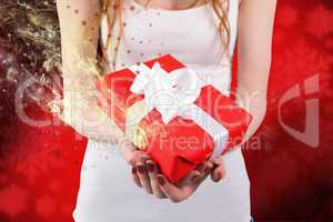 Composite image of woman holding red and white gift