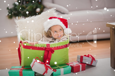 Composite image of cute little girl sitting in giant christmas g