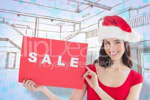 Composite image of festive brunette with sale sign