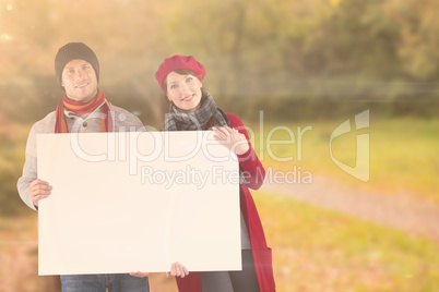 Composite image of couple holding a large sign
