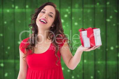 Composite image of stylish brunette in red dress holding gift