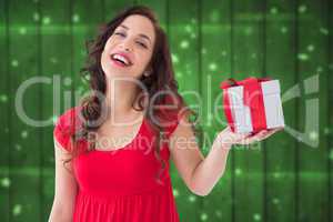 Composite image of stylish brunette in red dress holding gift