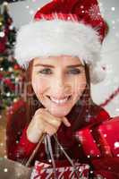 Composite image of festive redhead holding christmas gifts