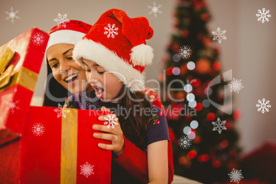 Composite image of festive mother and daughter opening a christm