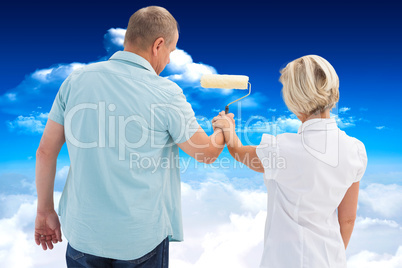 Composite image of happy older couple painting white wall