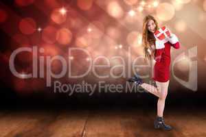Composite image of festive redhead holding a gift