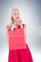 Stylish blonde in red dress opening gift bag