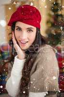 Composite image of surprised brunette on the couch at christmas
