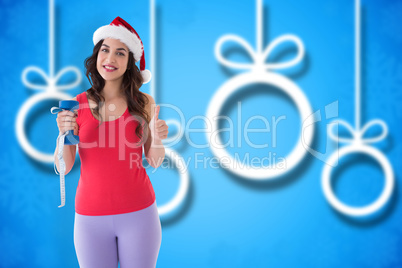 Composite image of festive fit brunette holding measuring tape a
