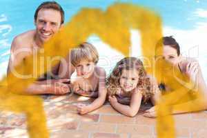 Composite image of happy family beside the swimming pool