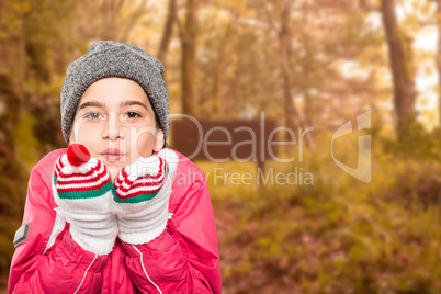 Composite image of wrapped up little girl blowing over hands