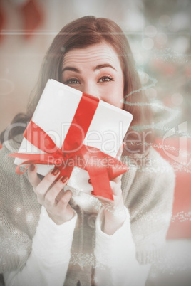 Composite image of brunette showing gift on the couch at christm