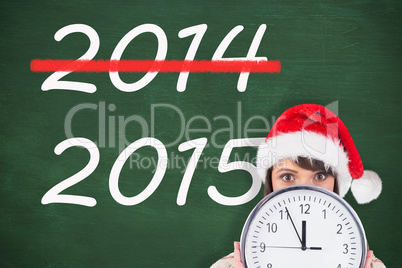 Composite image of festive brunette holding a clock