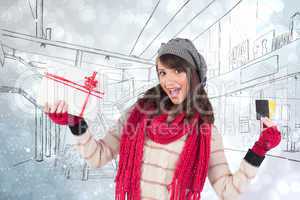 Composite image of brunette in winter clothes holding gift