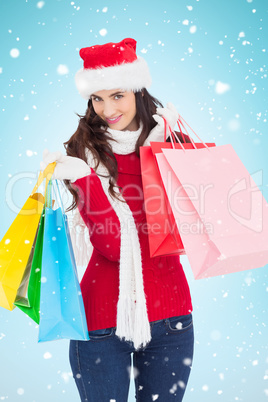Composite image of smiling brunette in winter wear holding shopp