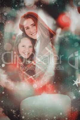 Composite image of festive mother and daughter wrapped in blanke