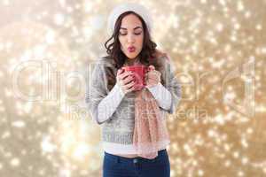 Composite image of brunette in winter clothes holding hot drink