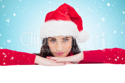 Composite image of pretty brunette in santa hat smiling at camer