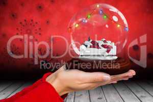 Composite image of hand holding santa snow globe