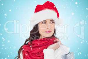 Composite image of brunette in santa hat holding shopping bag