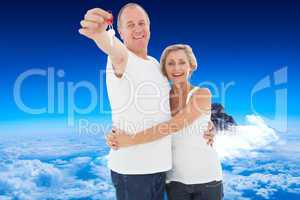 Composite image of mature couple smiling at camera with new hous